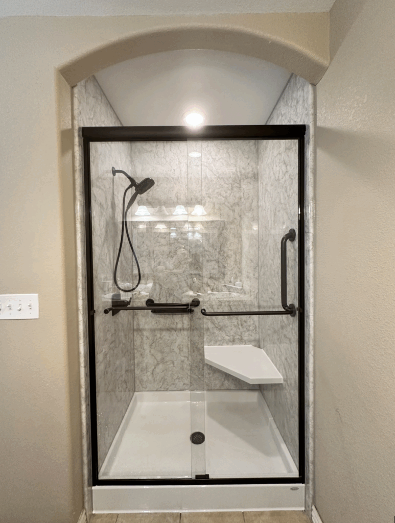 Photo of a walk in shower with a glass door enclosure and a bench seat